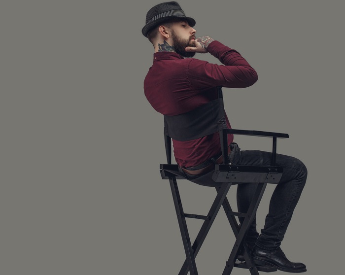 Man in hat sitting on film director's chair.