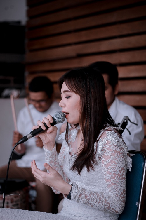 lady in white dress singing near two men